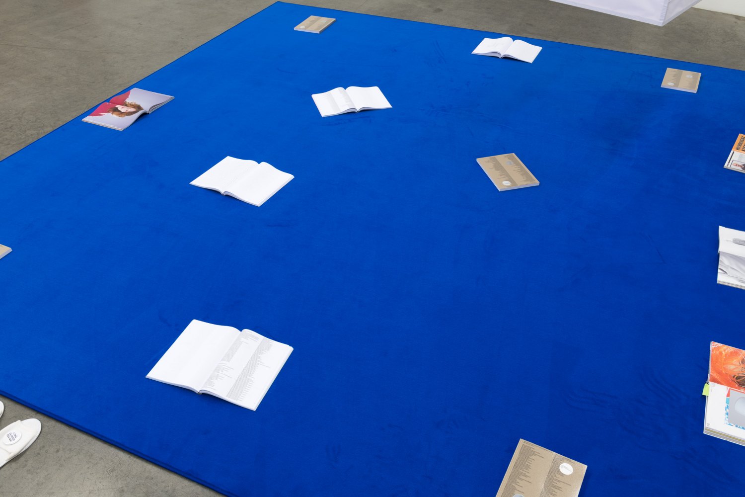 Karl Holmqvist TAPIS DE LECTURE (D’APRES DGF), 2021 Copy of artist’s book on carpet, Magazines, shoes and slippers dimensions variable