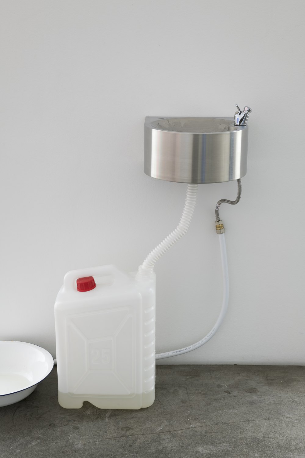 Claire Fontaine La mer à Boire, 2023 1000L blue water tank, pump, automatic pressure controller, 20 mm flexible hydraulic pipe, wall mounted drinking fountain, 80 mm drainage pipes, gerry can, cables, wall mountings and breeze blocks, mains water with 38 grams of salt per litre dimensions variable