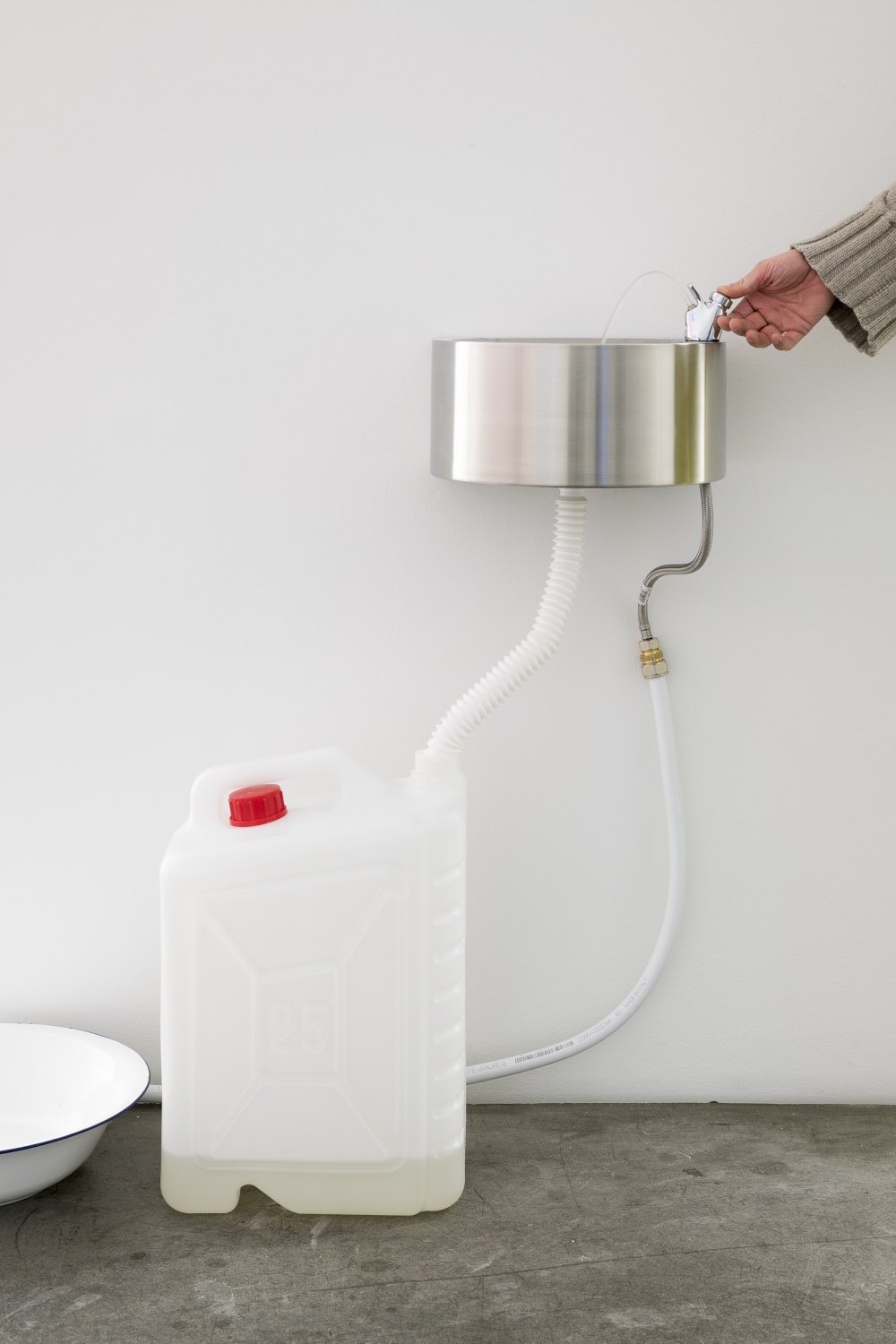 Claire Fontaine La mer à Boire, 2023 1000L blue water tank, pump, automatic pressure controller, 20 mm flexible hydraulic pipe, wall mounted drinking fountain, 80 mm drainage pipes, gerry can, cables, wall mountings and breeze blocks, mains water with 38 grams of salt per litre dimensions variable
